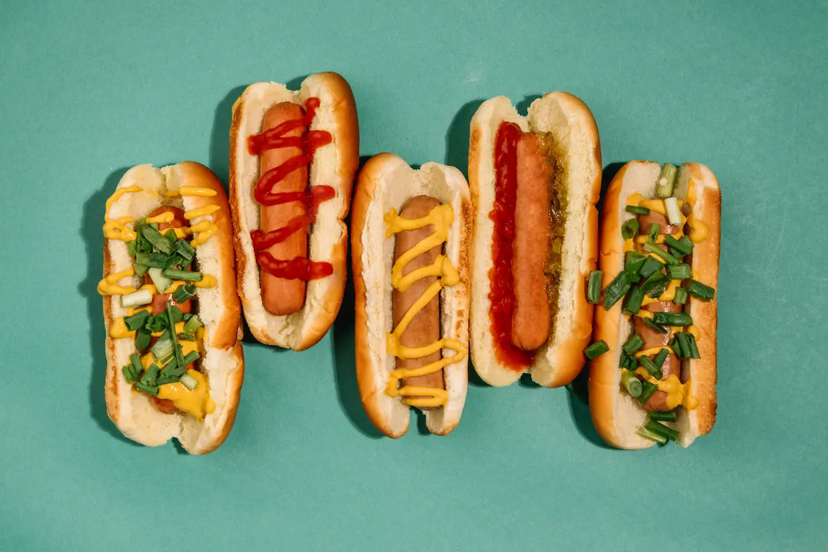 Five loaded sausage dogs with mustard, ketchup, and fresh toppings