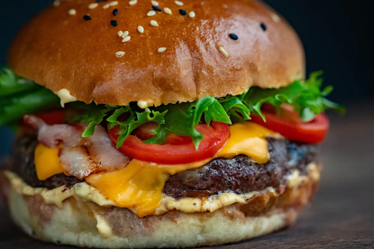 A bacon cheeseburger with fresh toppings on a brioche bun
