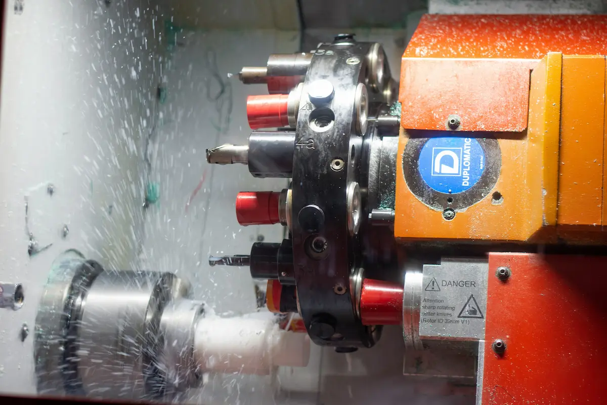 Machinist in safety goggles operating a CNC machine in an industrial workshop
