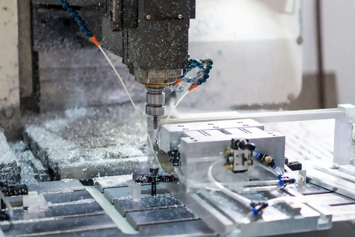 CNC milling machine spindle cutting an aluminum workpiece with coolant streams