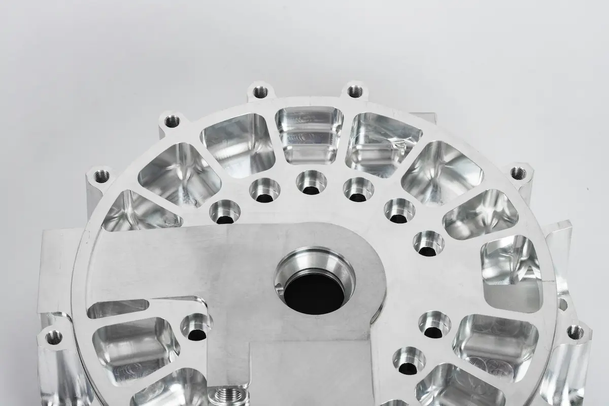 Round precision-machined aluminum housing showing pocketed face and threaded holes